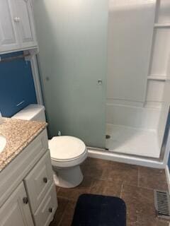 bathroom featuring vanity, toilet, and a shower with shower door