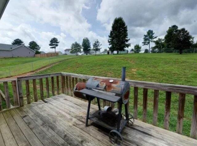 wooden deck with a lawn and a grill