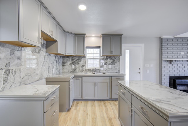 kitchen with light hardwood / wood-style flooring, a kitchen island, sink, gray cabinets, and decorative backsplash