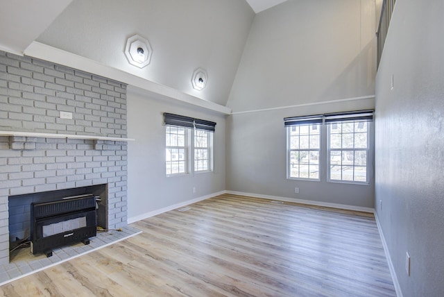 unfurnished living room with a fireplace, high vaulted ceiling, and light hardwood / wood-style flooring