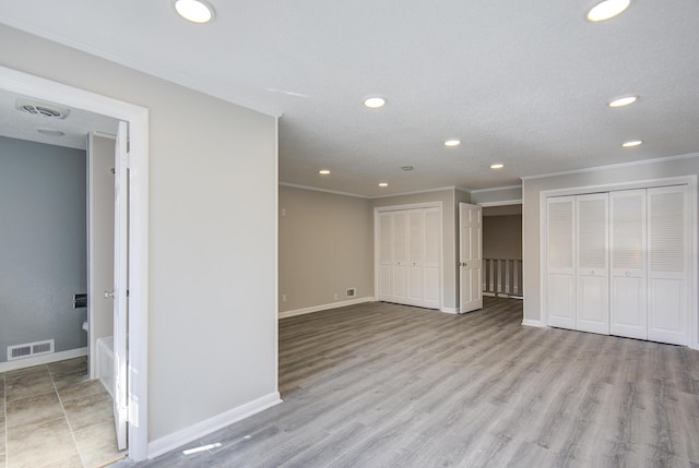 basement featuring light wood-type flooring, ornamental molding, and a textured ceiling