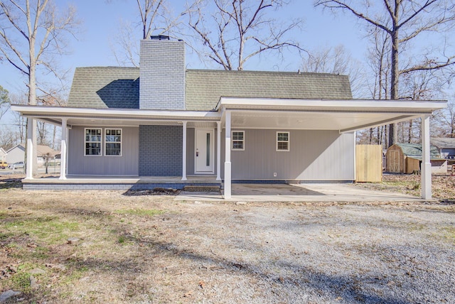 rear view of property with a porch, a storage unit, and a carport