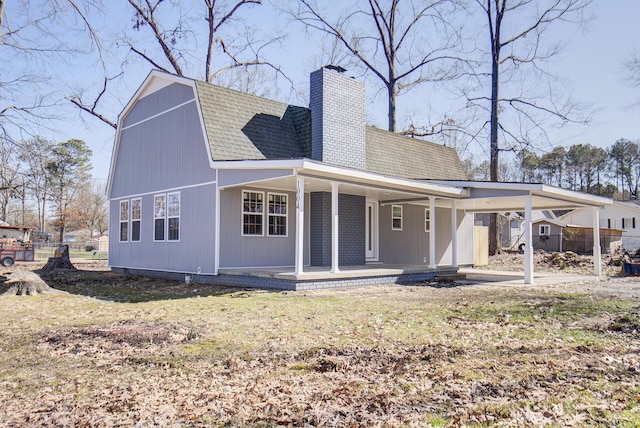 rear view of house with covered porch and a lawn