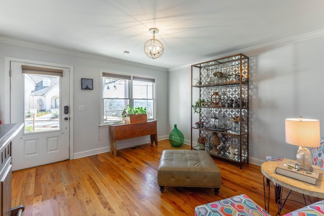 foyer entrance featuring crown molding, baseboards, light wood-type flooring, and a chandelier