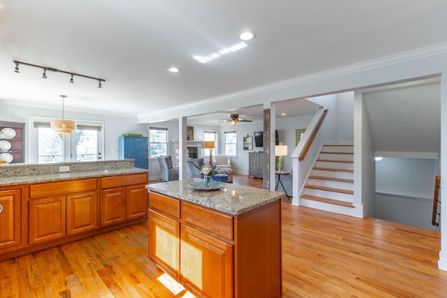 kitchen with crown molding, light wood-type flooring, ceiling fan, and light stone countertops