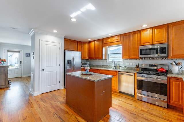 kitchen featuring light wood finished floors, a center island, appliances with stainless steel finishes, and a sink