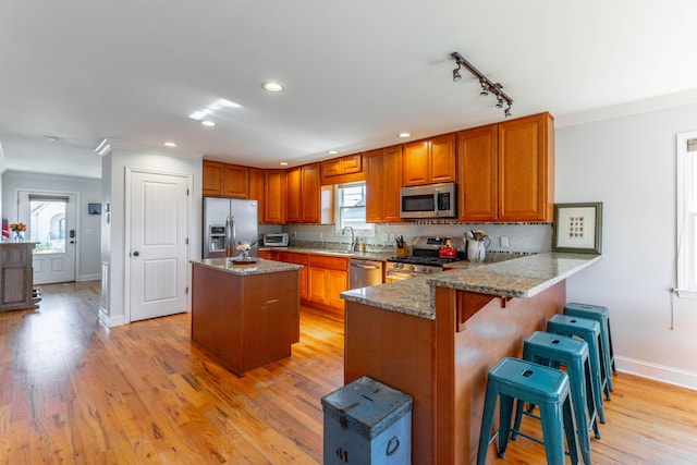 kitchen with a sink, a healthy amount of sunlight, brown cabinetry, and stainless steel appliances