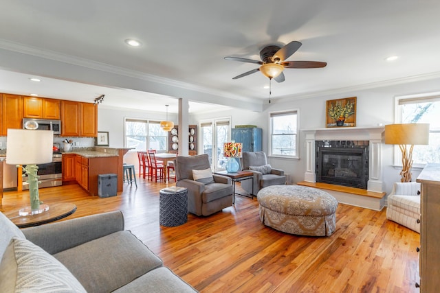 living area with a wealth of natural light, crown molding, and light wood-type flooring