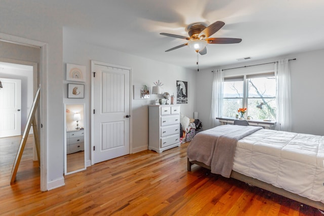 bedroom with light wood-style flooring, baseboards, visible vents, and ceiling fan