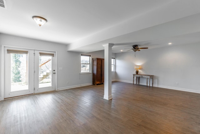 unfurnished living room featuring dark wood finished floors, a ceiling fan, baseboards, and ornate columns