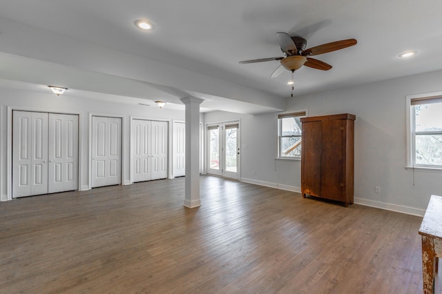 unfurnished bedroom with decorative columns, wood finished floors, baseboards, and two closets