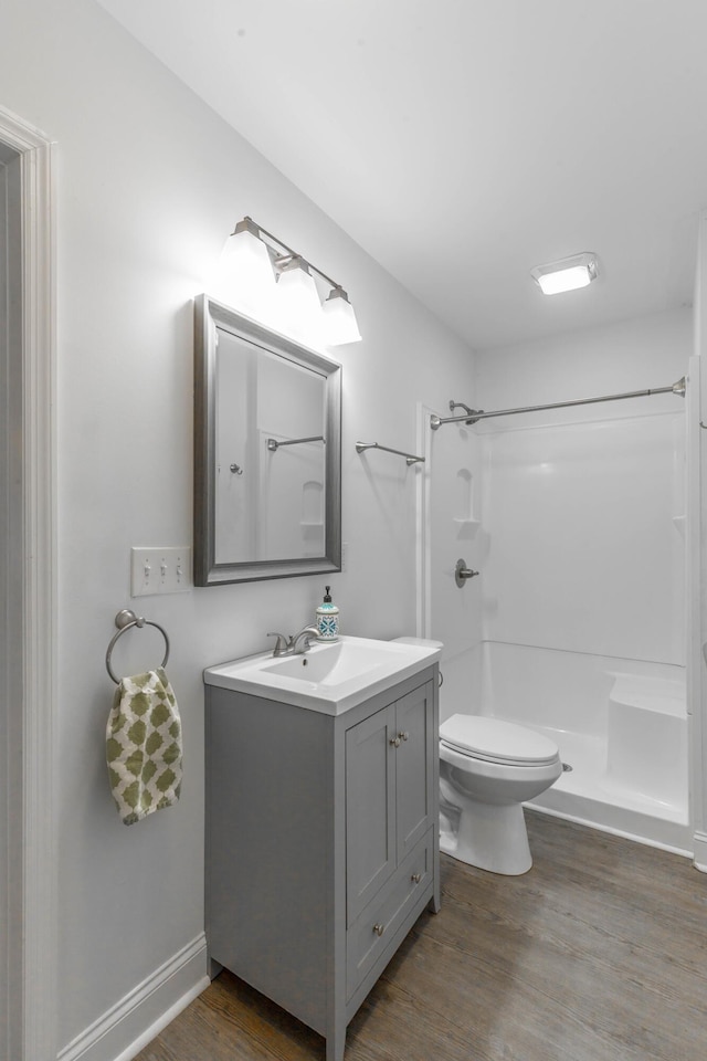 bathroom with vanity, toilet, a shower, and wood finished floors