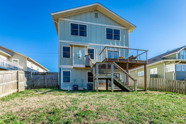 rear view of house featuring a wooden deck, board and batten siding, a fenced backyard, and stairs