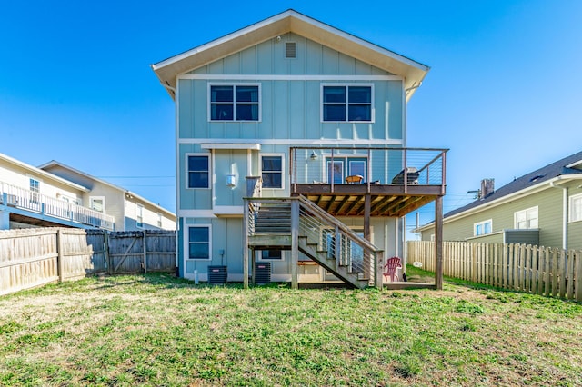 back of property featuring board and batten siding, a wooden deck, stairs, a lawn, and a fenced backyard