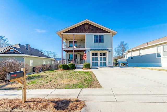 view of front facade with board and batten siding, a front yard, a garage, a balcony, and driveway