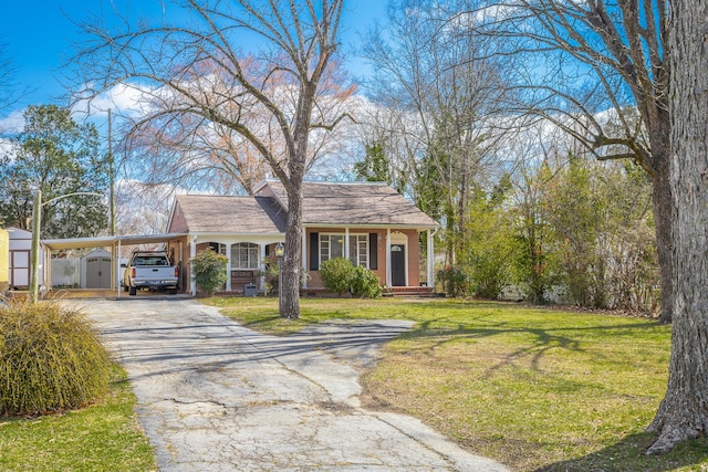 view of front of house featuring aphalt driveway, an outbuilding, a storage unit, a carport, and a front yard