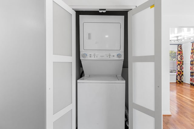 laundry room featuring laundry area, light wood finished floors, and stacked washing maching and dryer