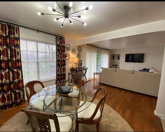 dining room featuring built in features, a notable chandelier, and wood finished floors