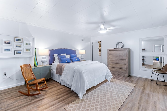 bedroom featuring baseboards, visible vents, a ceiling fan, light wood-style flooring, and crown molding