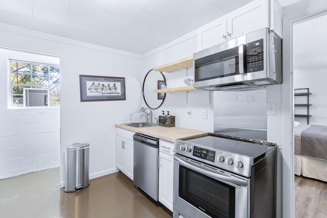 kitchen featuring baseboards, appliances with stainless steel finishes, white cabinetry, open shelves, and a sink