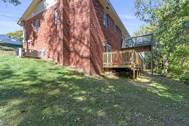 view of side of property featuring brick siding, a yard, a deck, and central AC unit