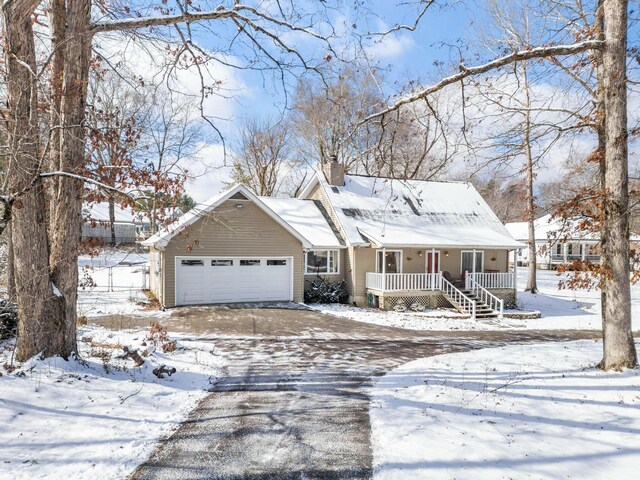 view of front of house with covered porch, a chimney, and an attached garage