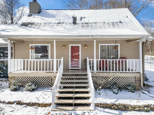 view of front facade featuring covered porch and a chimney