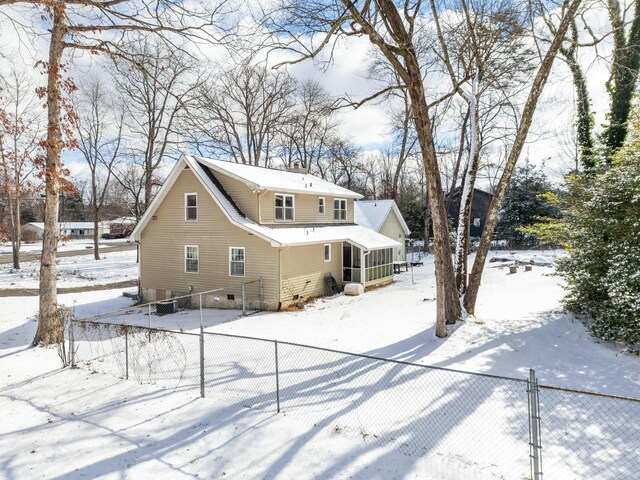 snow covered property with a sunroom and fence