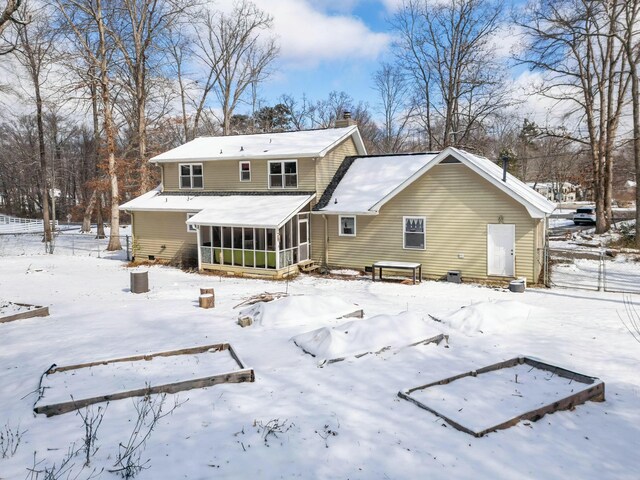 snow covered back of property with entry steps, a sunroom, and a chimney