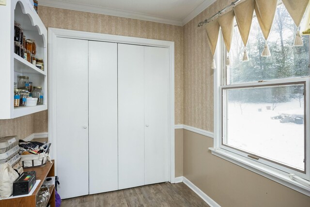 unfurnished bedroom featuring baseboards, a closet, ornamental molding, and wood finished floors