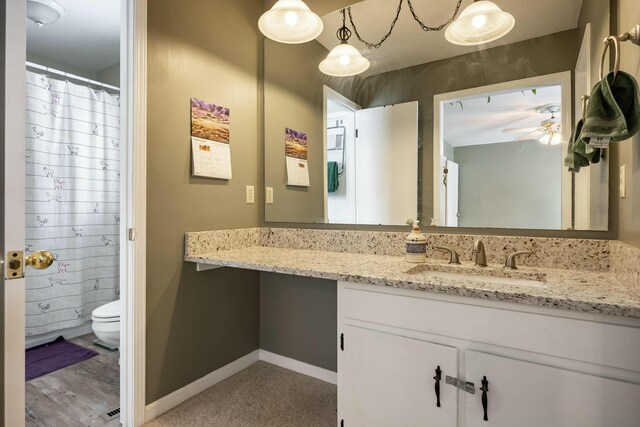 bathroom featuring ceiling fan, vanity, toilet, and baseboards