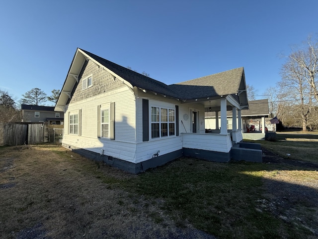 view of side of property with covered porch and a yard