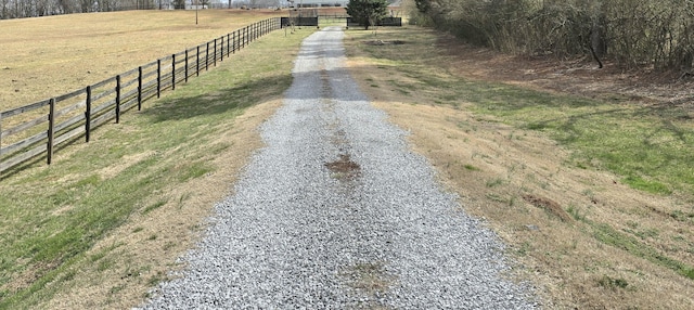 view of yard with gravel driveway, fence, and a rural view