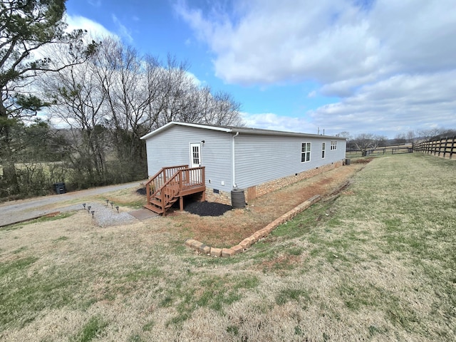 view of property exterior with crawl space, fence, and a lawn