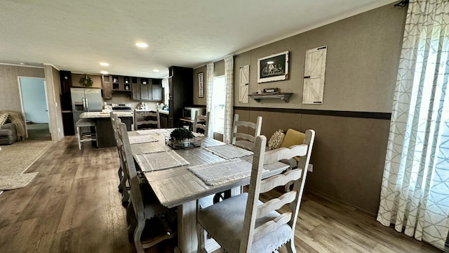 dining space featuring a wainscoted wall, wood finished floors, and recessed lighting