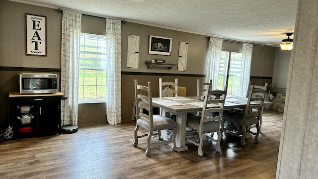 dining room featuring a textured ceiling, a ceiling fan, wood finished floors, and ornamental molding