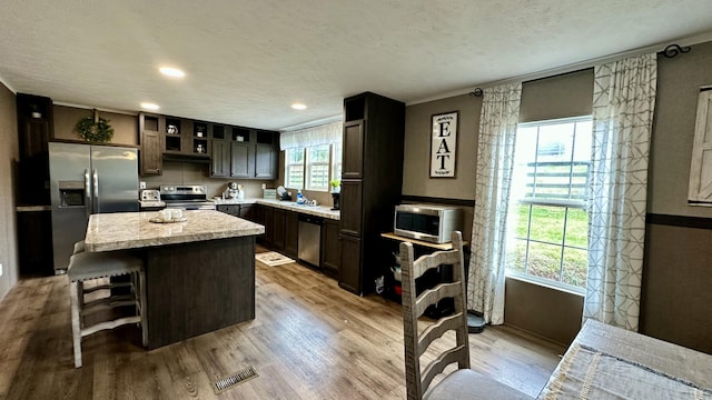 kitchen with visible vents, light wood-style flooring, appliances with stainless steel finishes, a center island, and a textured ceiling