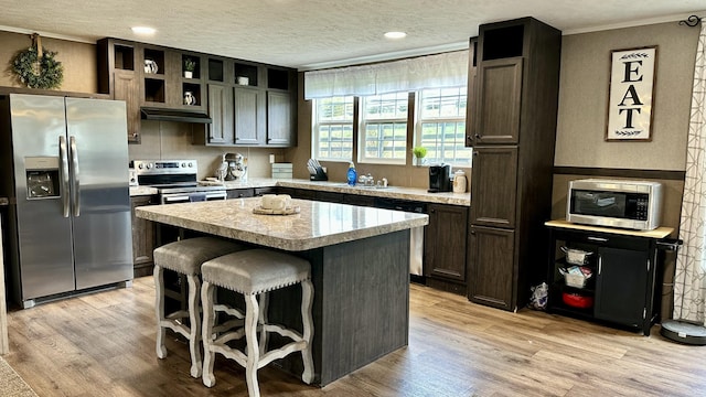 kitchen with light wood-style flooring, a center island, stainless steel appliances, a textured ceiling, and light countertops