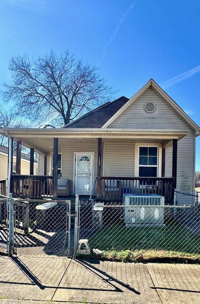 view of front of home featuring a fenced front yard, roof with shingles, covered porch, and a gate