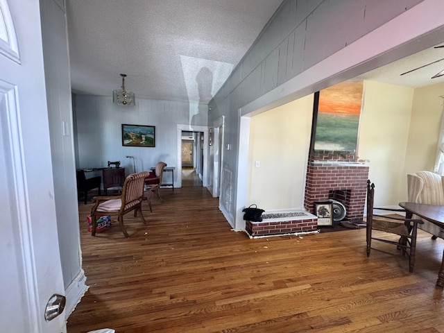 interior space with a textured ceiling, an inviting chandelier, wood finished floors, and a fireplace