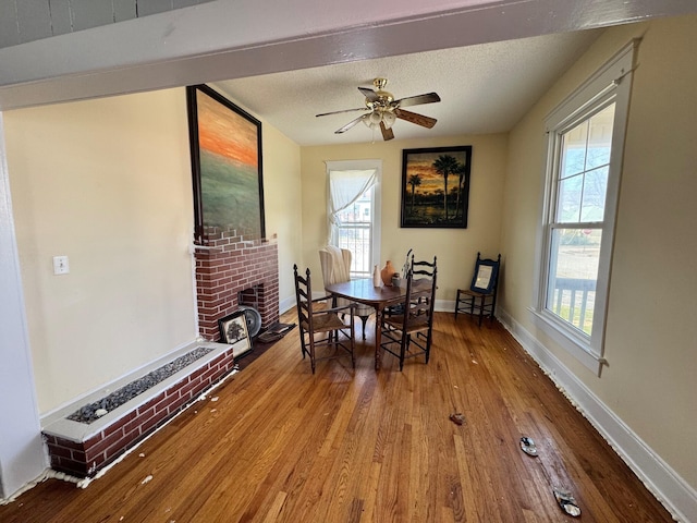 dining area with baseboards, a textured ceiling, ceiling fan, and hardwood / wood-style flooring