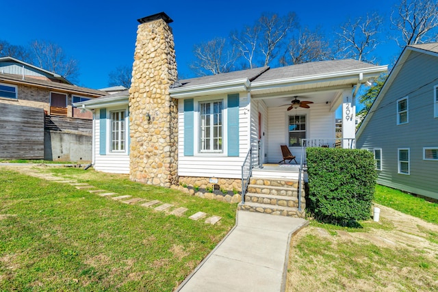 view of front of home featuring covered porch, a chimney, a front yard, and a ceiling fan