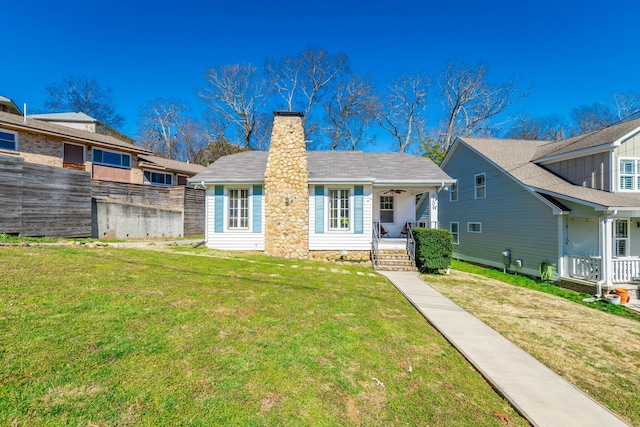 view of front of property featuring covered porch, a chimney, and a front lawn