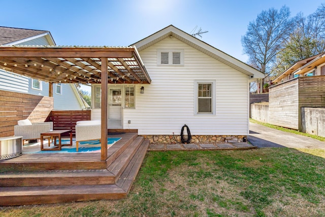 rear view of house with a deck, a lawn, and fence