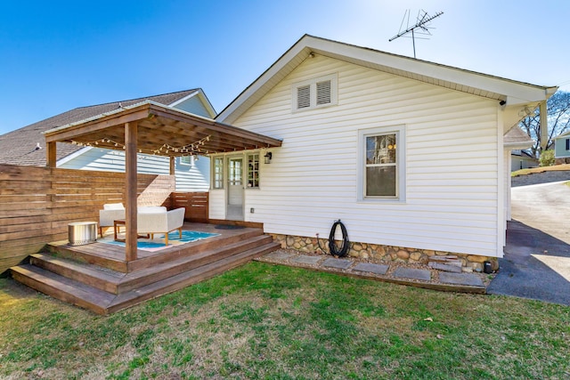 back of property featuring a deck, a lawn, and fence