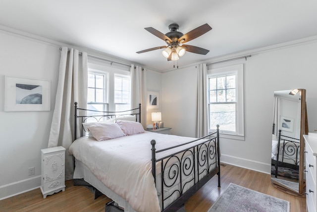 bedroom featuring multiple windows, baseboards, and wood finished floors