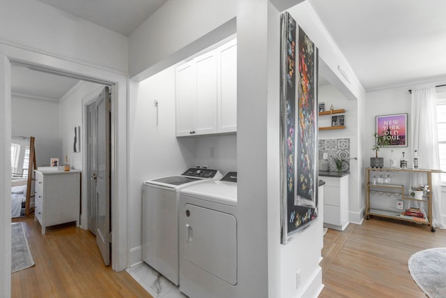 laundry area featuring light wood-type flooring, independent washer and dryer, cabinet space, and crown molding