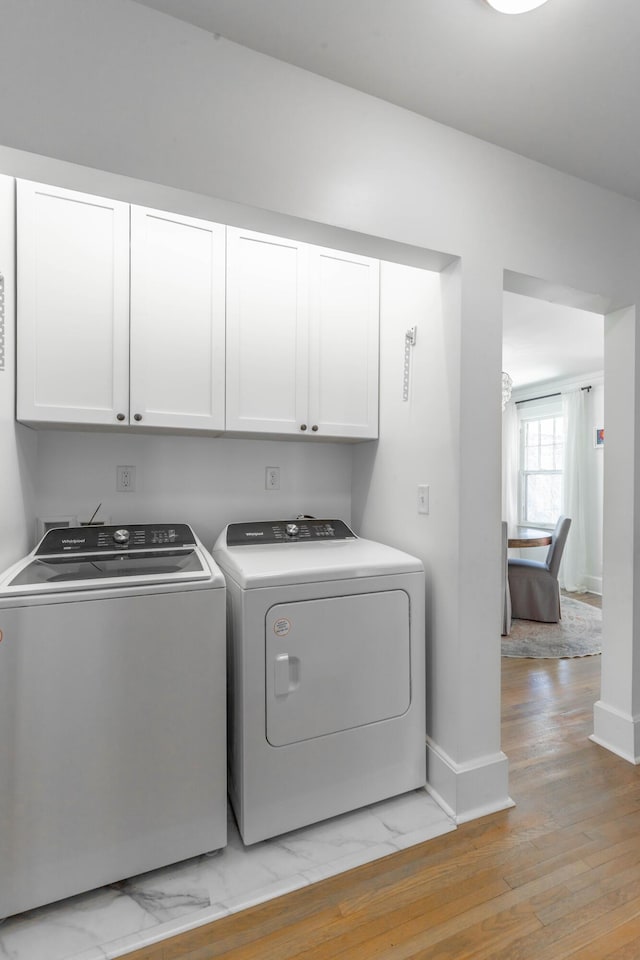 clothes washing area with baseboards, marble finish floor, cabinet space, and washer and dryer