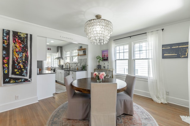 dining space featuring plenty of natural light, a notable chandelier, baseboards, and wood finished floors