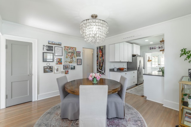 dining area with a chandelier, light wood-style floors, baseboards, and ornamental molding